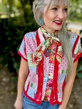 Woman wearing a colorful patterned shirt with a scarf, standing outdoors.