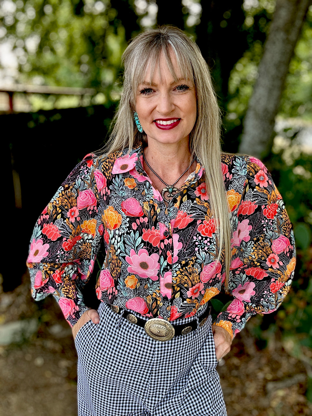 Woman wearing a colorful floral blouse with a blurred natural background