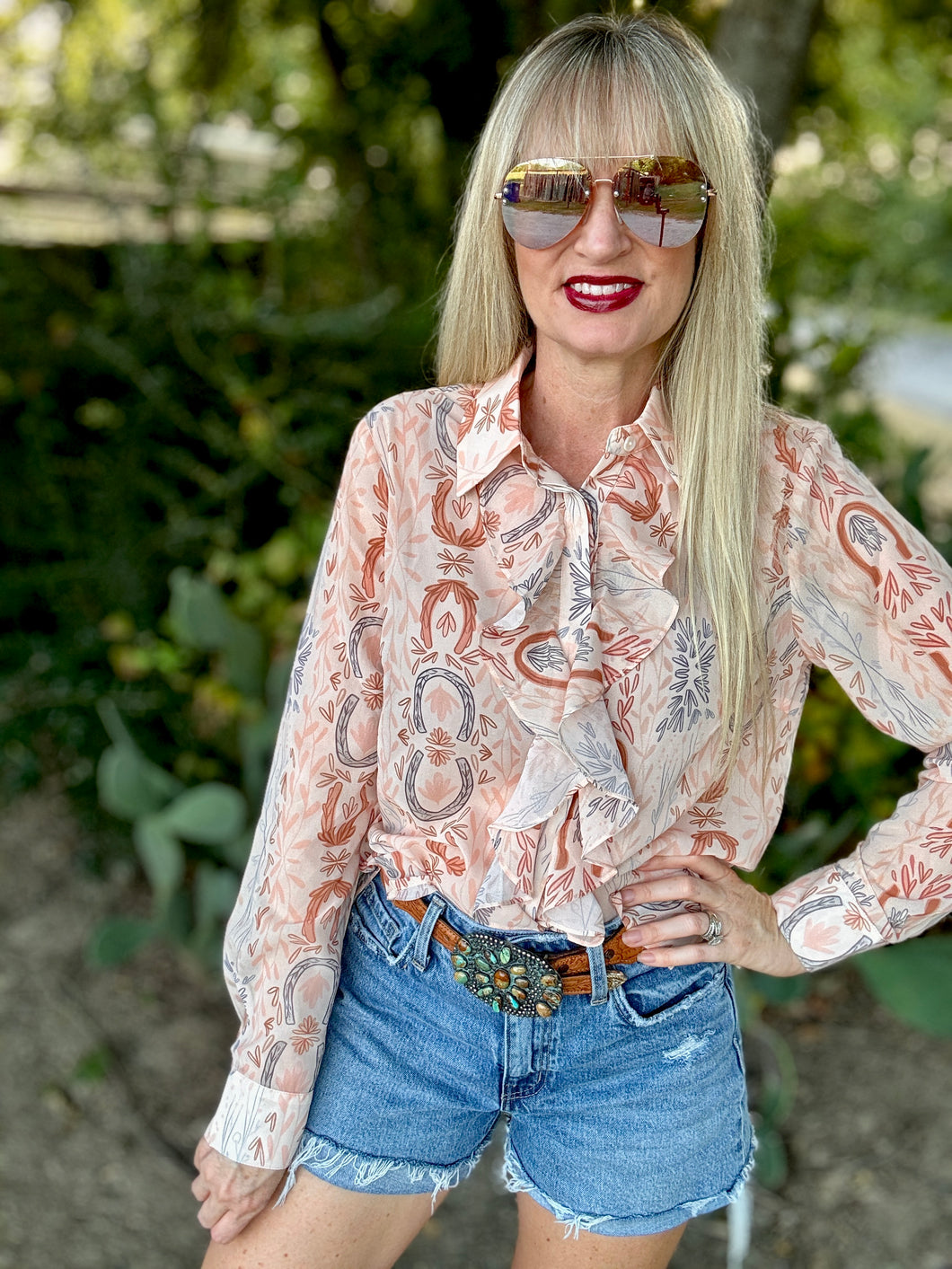 Woman wearing a patterned blouse and denim shorts outdoors