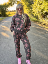 Woman in a floral tracksuit standing on a road with trees in the background