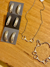 silver jewelry including earrings and a necklace on a wooden surface