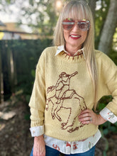 Person wearing a yellow sweater with a horse design outdoors