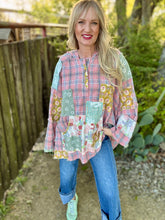 Woman wearing a patchwork shirt outdoors with greenery in the background
