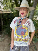 Woman wearing a white graphic t-shirt with colorful design outdoors