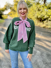 Woman wearing a green sweater with a large red and white bow blouse outdoors