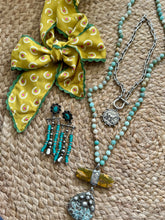 Jewelry set with a green bow on a textured surface