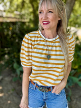Woman wearing a yellow and white striped shirt with blue jeans outdoors.