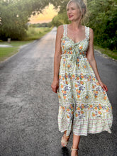 Woman in a floral dress standing on a road with trees in the background