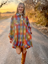 Woman in a colorful plaid dress standing on a road with a scenic background