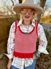 Person wearing a red and white patterned top with a beige hat and sunglasses outdoors.