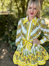 Woman wearing a floral dress with yellow accents outdoors
