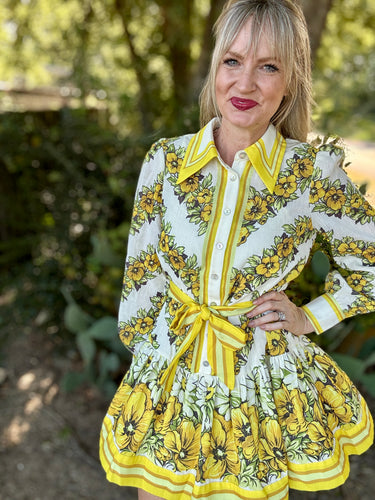 Woman wearing a floral dress with yellow accents outdoors