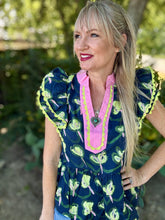 Woman wearing a colorful blouse with a floral pattern outdoors