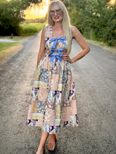 Woman in a patterned dress standing on a road with trees in the background