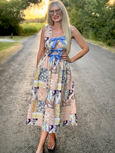 Woman in a patterned dress standing on a road with trees in the background