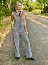 Woman in a checkered outfit standing on a road with trees in the background