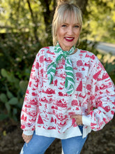 Woman wearing a red and white patterned blouse with a green scarf outdoors.