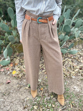 Person wearing brown pants with a belt in front of cacti