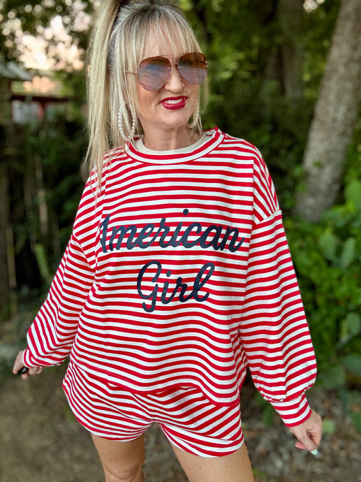 Woman wearing a red and white striped outfit with 'American Girl' text outdoors.