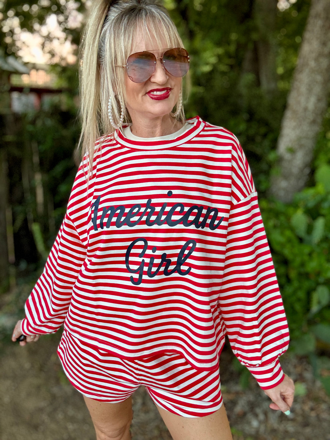 Woman wearing a red and white striped outfit with 'American Girl' text outdoors.