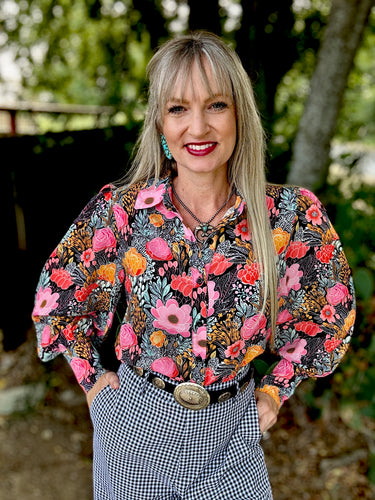 Woman wearing a colorful floral blouse with a blurred natural background