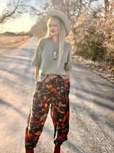Woman in a patterned outfit standing on a road with trees in the background
