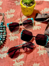 Sunglasses with turquoise embellishments on a patterned surface