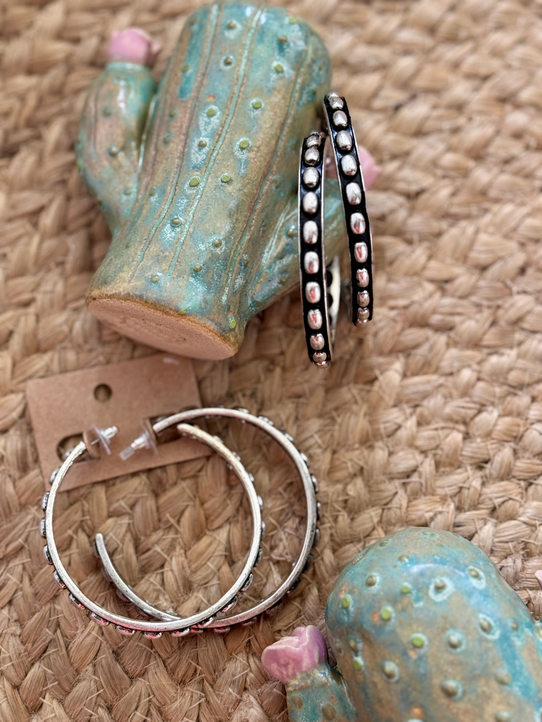 Silver hoop earrings on a textured surface with decorative cacti