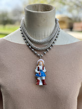 Necklace with a pendant of a person in a dress on a mannequin.