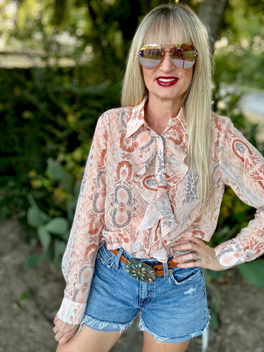 Woman wearing a patterned blouse and denim shorts outdoors