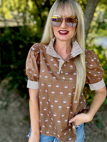 Woman wearing a brown floral blouse with sunglasses outdoors
