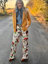 Woman standing on a road wearing a mustard cardigan, patterned pants, and brown boots.