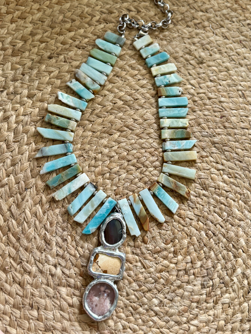 Necklace with turquoise and silver elements on a textured beige surface