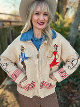 Woman wearing a patterned sweater with a blue shirt underneath, standing outdoors.