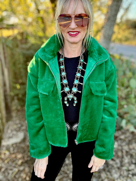 Person wearing a green jacket with a blurred natural background
