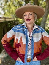 Woman wearing a patterned cardigan with a cowboy hat outdoors