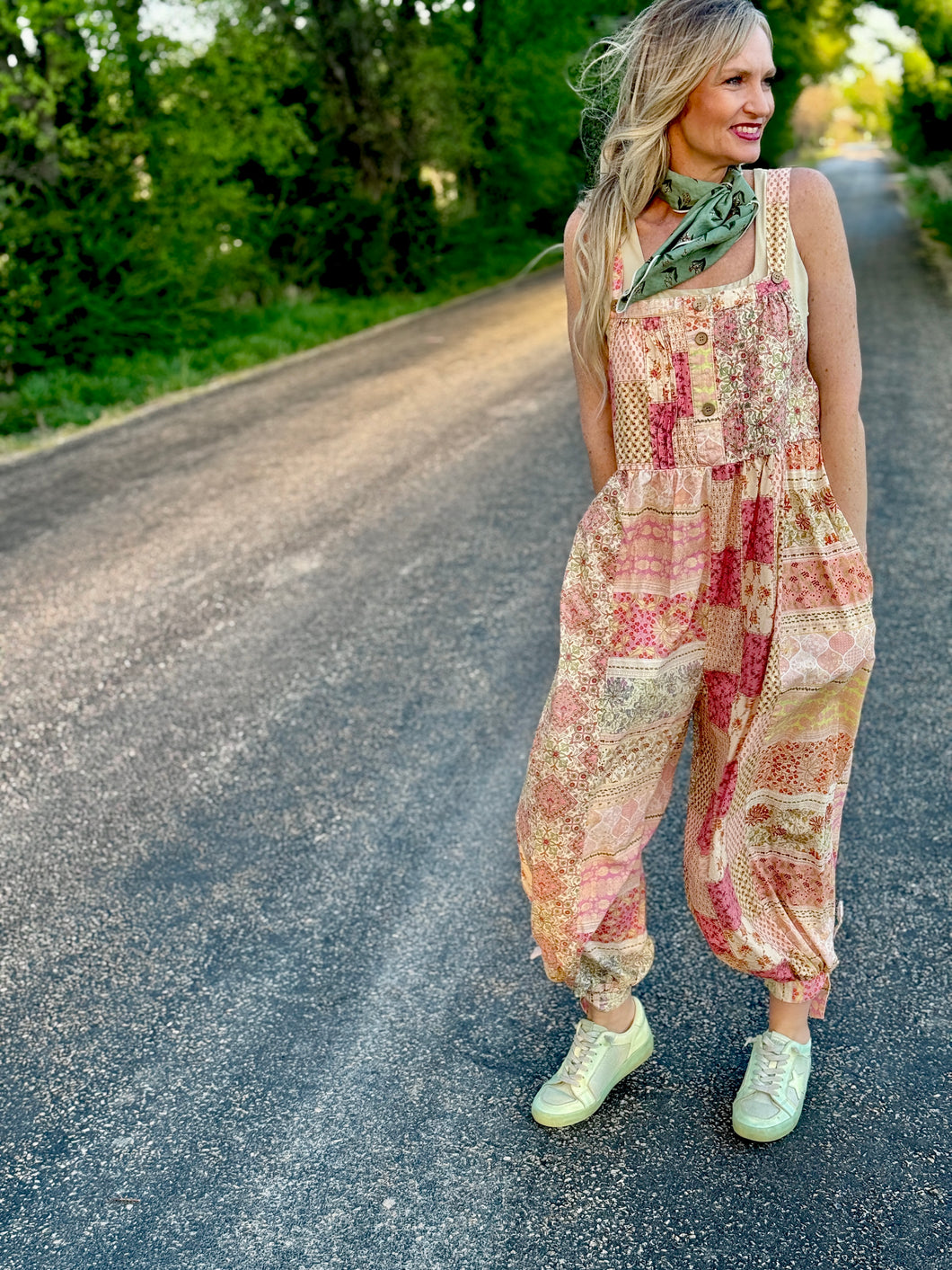 Woman in a patterned jumpsuit standing on a road with greenery in the background