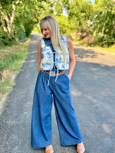 Woman in a blue outfit standing on a road with trees in the background