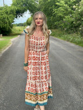 Woman in a patterned dress standing on a road with greenery in the background