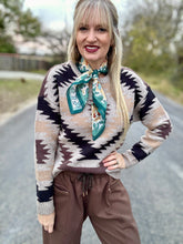 Woman wearing a patterned sweater and scarf standing on a road.