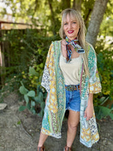 Woman wearing a colorful kimono-style garment with a patterned scarf outdoors.