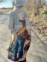Person wearing a long, patterned duster with a graphic of a cowboy on a road.