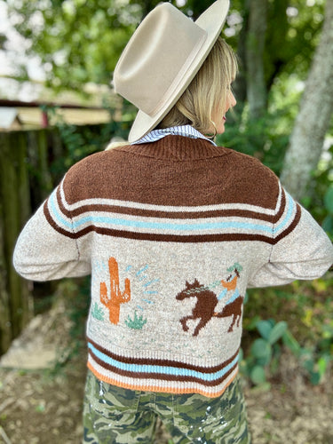 Person wearing a patterned sweater with desert-themed designs outdoors.