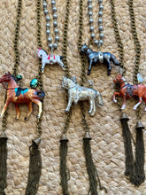 Necklaces with horse pendants on a textured surface