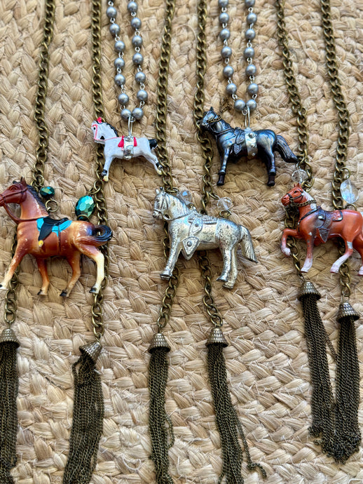 Necklaces with horse pendants on a textured surface