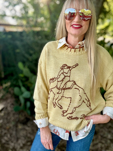 Woman wearing a yellow sweater with a horse design outdoors