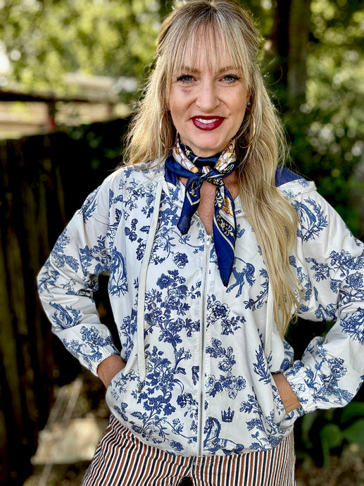 Woman wearing a blue and white floral blouse with a scarf, standing outdoors.
