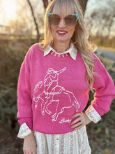 Woman wearing a pink sweater with a horse design outdoors