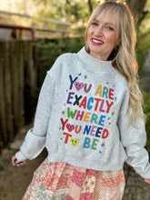 Woman wearing a gray sweatshirt with colorful text outdoors
